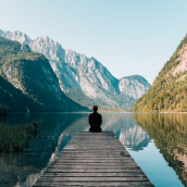 person sat at a lake between mountains