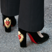 Femme avec des chaussures à talons hauts Louboutin en velours noir avec un design en forme de cœur avant le défilé Prada, la semaine de la mode de Milan street style le 18 juin 2017 à Milan.