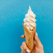cône de crème glacée sur fond bleu. La femme tenant la glace à la main.