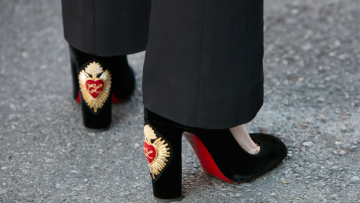 Femme avec des chaussures à talons hauts Louboutin en velours noir avec un design en forme de cœur avant le défilé Prada, la semaine de la mode de Milan street style le 18 juin 2017 à Milan.